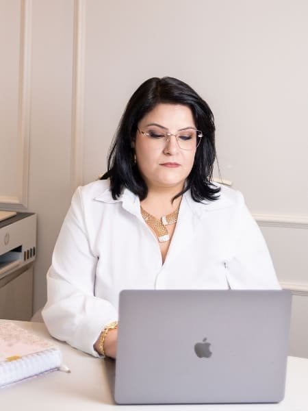 Fotografia da Dra. Francine, sentada à frente de seu computador atendendo as necessidades do Direito da Saúde de seus pacientes.