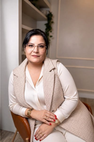 Fotografia da Dra. Francine, sentada em seu escritório, atenta as necessidades relacionadas ao Direito da Saúde de seus pacientes.